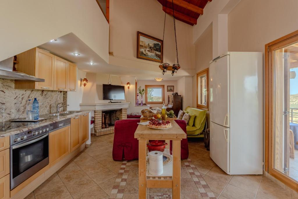 a kitchen with a table and a white refrigerator at Villa Sternfalle with jacuzzi by 8essentially in Elaía