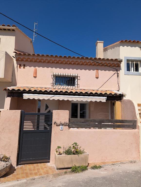 une maison avec une porte noire et un balcon dans l'établissement Location saisonnière bord de mer Martigues Carro, à Martigues