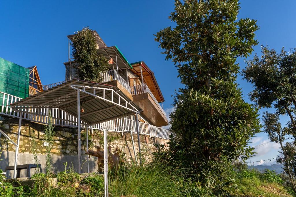 una casa en una colina con un árbol en The Frozen Valley 4BHK Villa, en Mukteshwar
