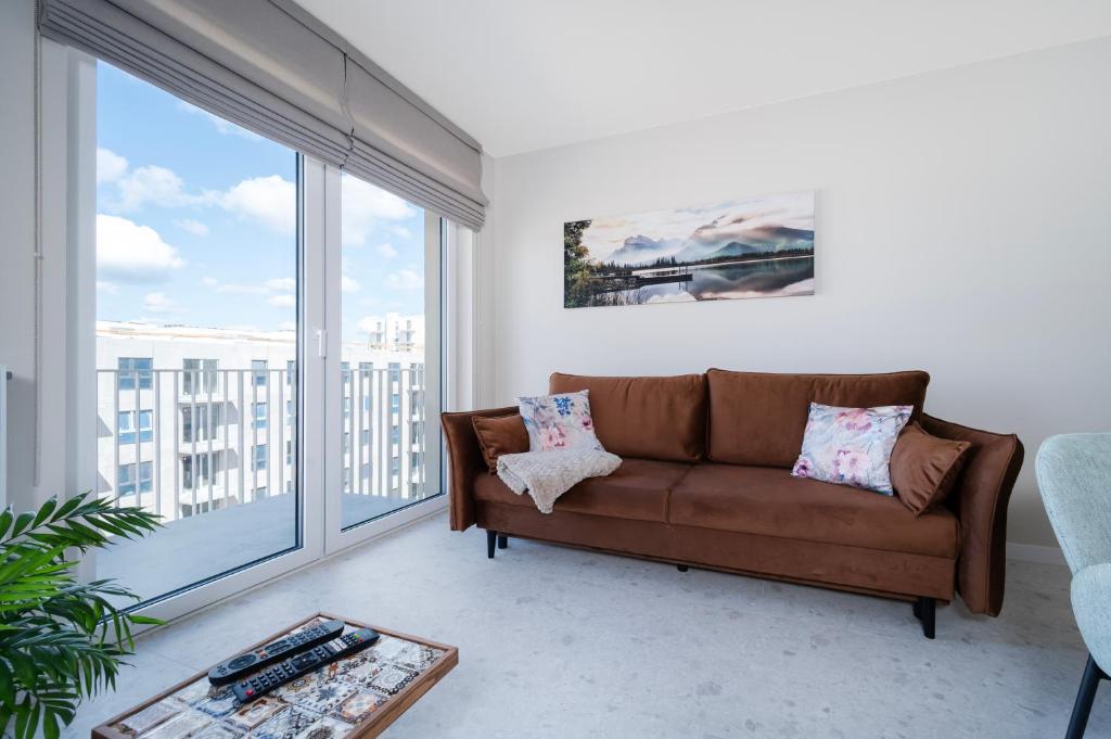 a living room with a couch and a large window at Widzewska Chic Apartment by BookingHost in Łódź