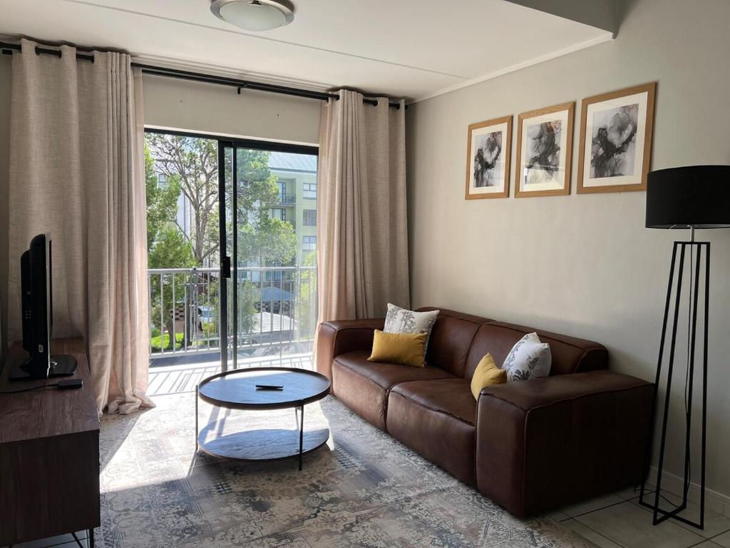 a living room with a brown couch and a glass table at Greenlee Lifestyle Apartment- 2 Bedroom in Sandton