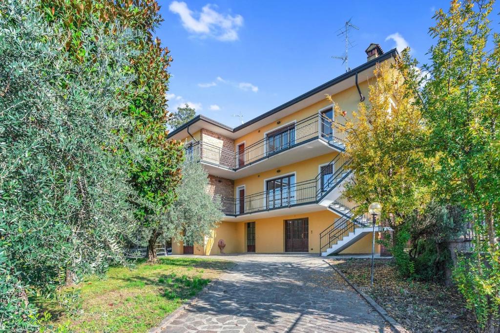 an exterior view of a large yellow house with trees at Villa Carli by Aurora - Superior Apartment in Soiano del Lago