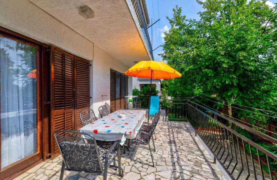 a table and chairs with an umbrella on a balcony at Apartment in Jadranovo 39395 in Jadranovo