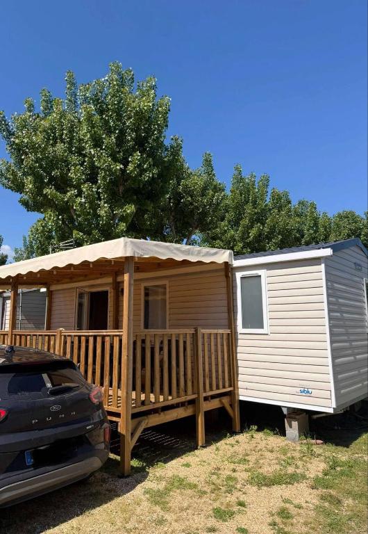 une petite maison avec un porche et une terrasse dans l'établissement Mobil Home - Camping siblu les sables du midi - Valras Plage, à Sérignan