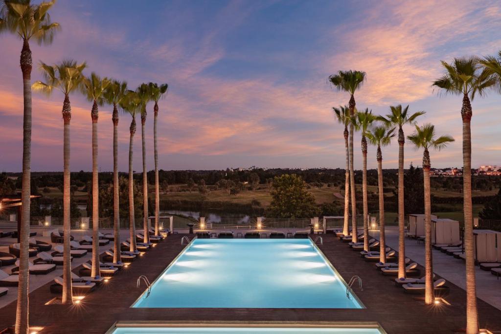a resort pool with palm trees and lounge chairs at Victoria Golf Resort and Spa Managed by Accor in Vilamoura