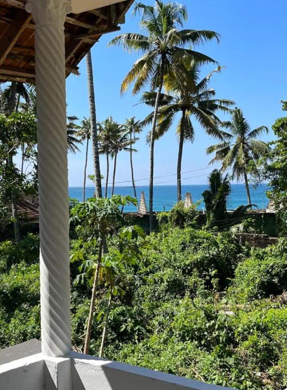 a view from the porch of a resort with palm trees at Guru villa near beach in Varkala