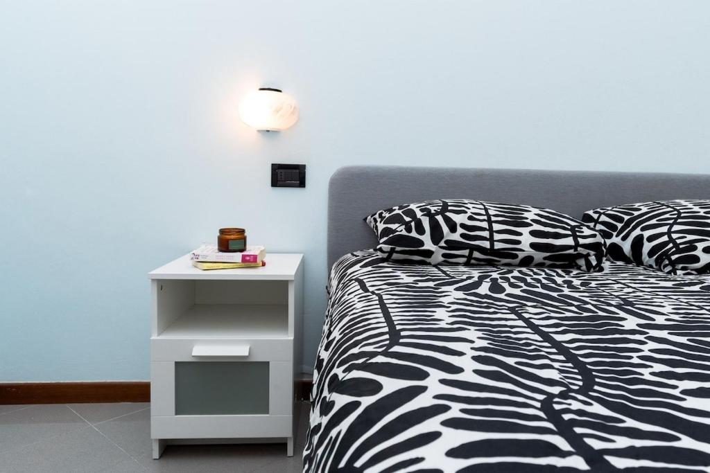 a bed with a black and white comforter and a side table at Dolce Riviera Marina Centro in Rimini