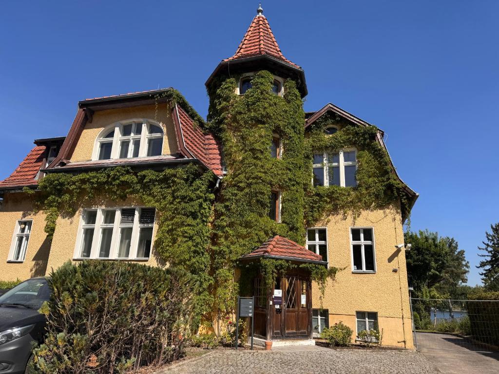 an ivy covered building with a gate in front at Villa am Peetzsee in Schlangenluch
