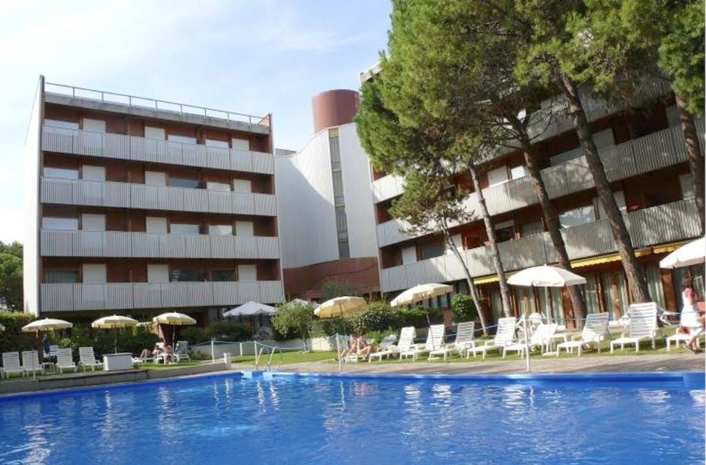 een zwembad tegenover een hotel met stoelen en parasols bij Euro Residence in Lignano Sabbiadoro