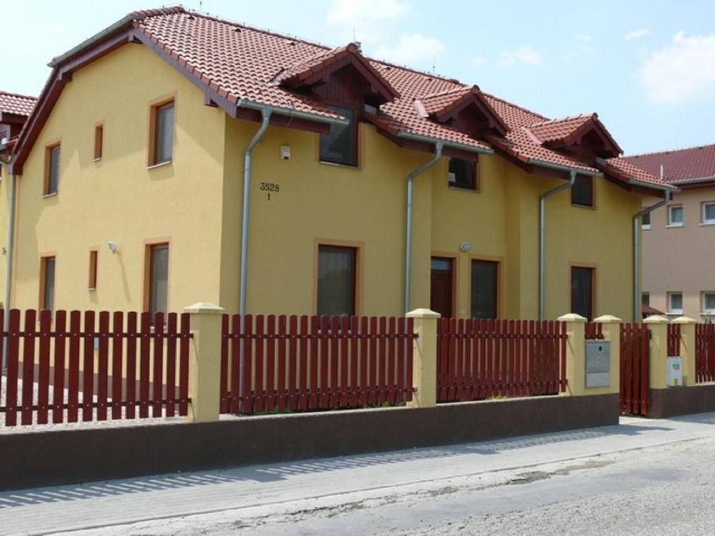 a yellow house with a wooden fence at Aquasleep in Veľký Meder