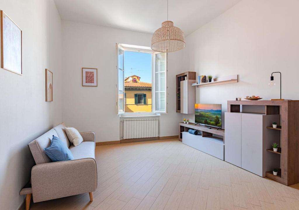 a living room with a couch and a tv and a window at -Cavour 8- 3 rooms with views - near the Tower in Pisa