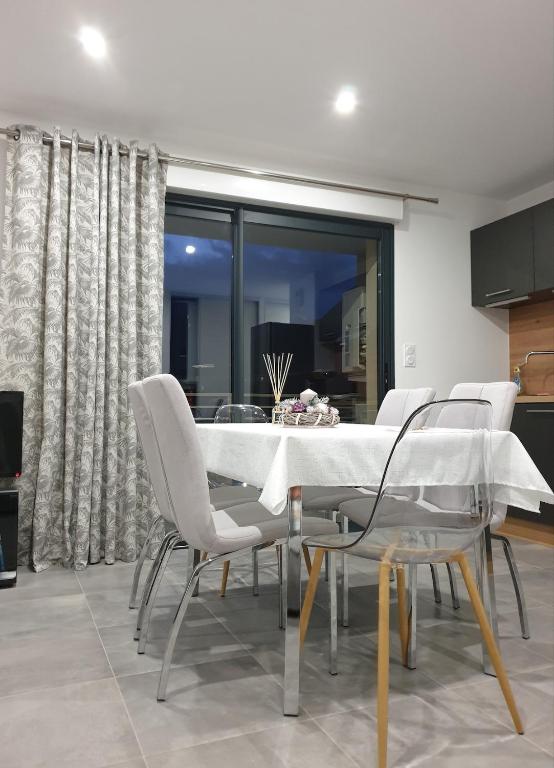 une salle à manger avec une table et des chaises blanches dans l'établissement T3 Corté vue sur la Citadelle, à Corte