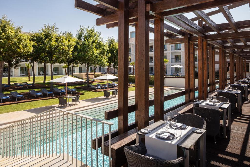 an outdoor patio with tables and chairs and a pool at Victoria Golf Resort and Spa Managed by Accor in Vilamoura