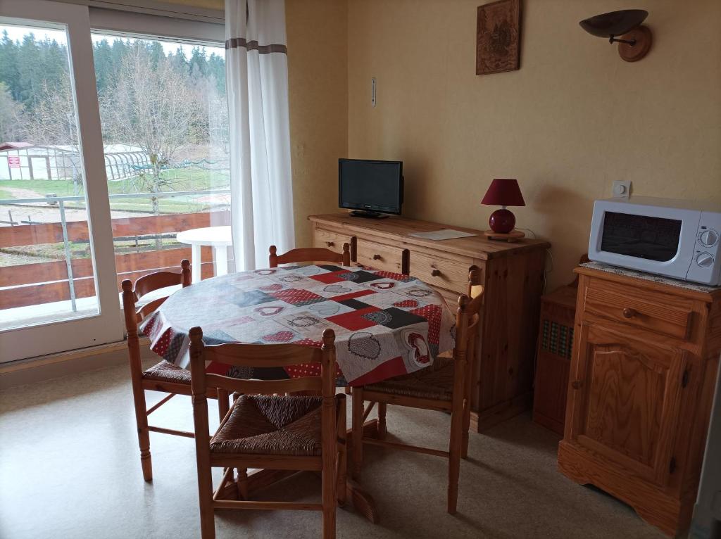a dining room with a table and a tv on a cabinet at Studio-cabine Résidence les Rennes in Prémanon