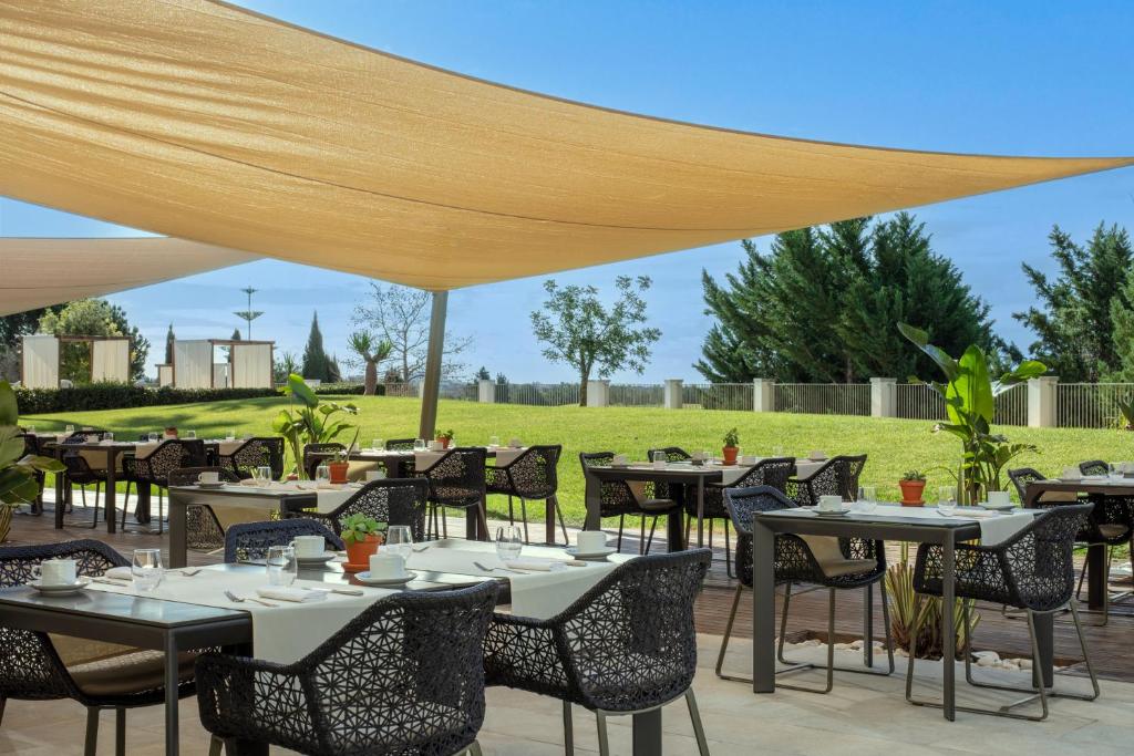 a restaurant with tables and chairs under a canopy at Victoria Golf Resort and Spa Managed by Accor in Vilamoura