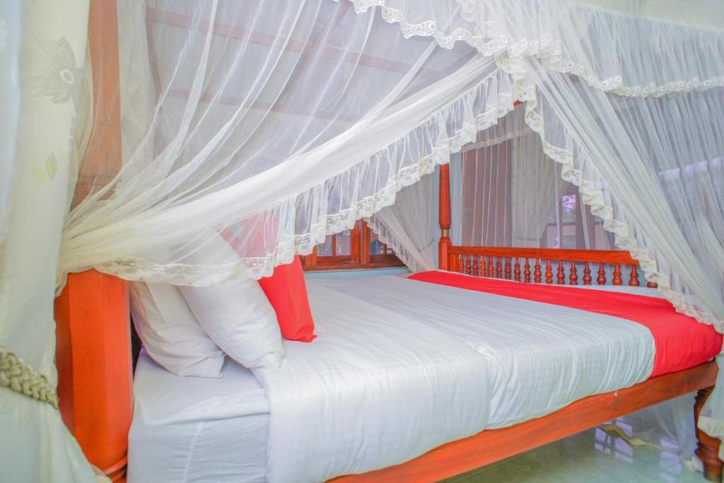 a bedroom with a canopy bed with red and white pillows at Madoldu Eco Resort in Ahangama