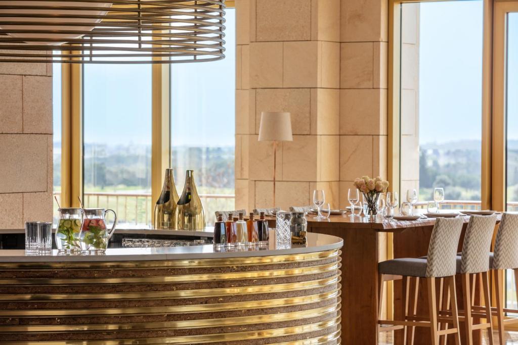 a restaurant with a bar with chairs and wine bottles at Victoria Golf Resort and Spa Managed by Accor in Vilamoura