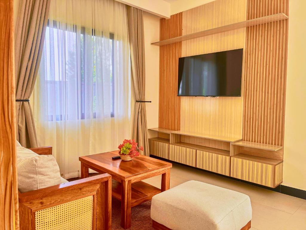 sala de estar con TV, silla y mesa en Ritzy Arcadia Cottages, en Arusha