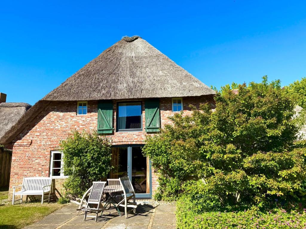 ein Haus mit Strohdach und Stühlen davor in der Unterkunft Stallteil in Oldsum