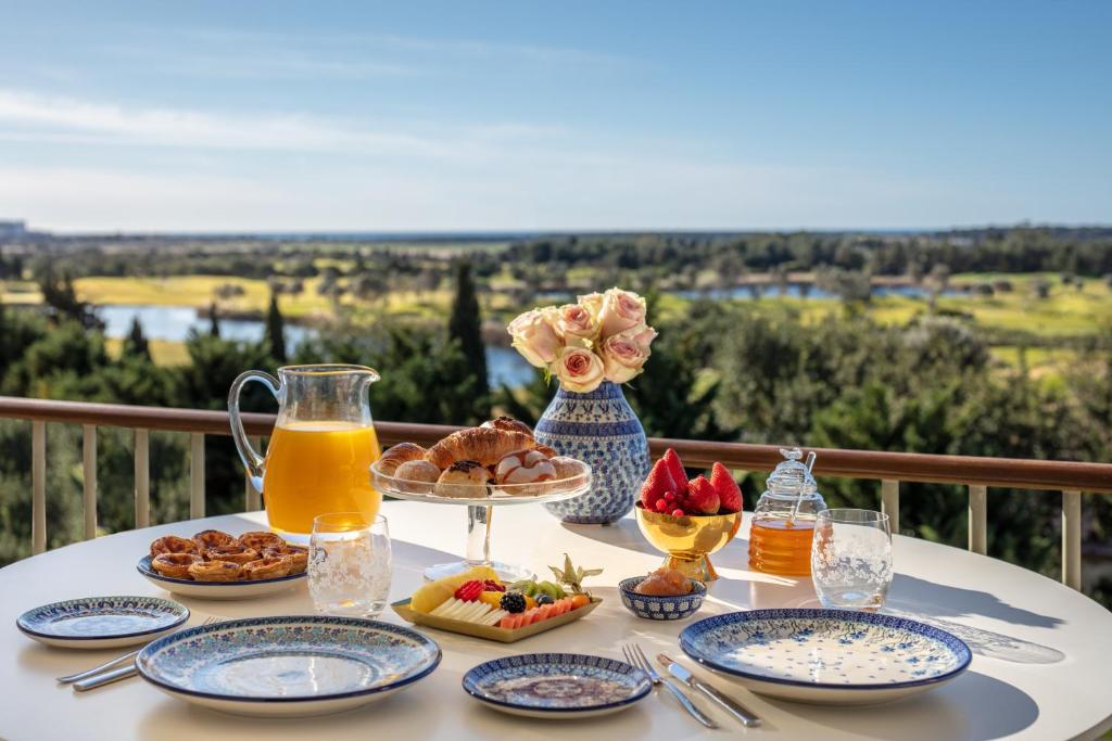 a table with breakfast foods and juice on a balcony at Victoria Golf Resort and Spa Managed by Accor in Vilamoura