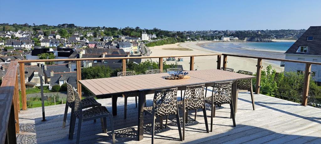 - une table et des chaises sur une terrasse avec vue sur la plage dans l'établissement Maison spacieuse Morgat Vue mer imprenable 5 chambres, terrasse XXL, à Crozon
