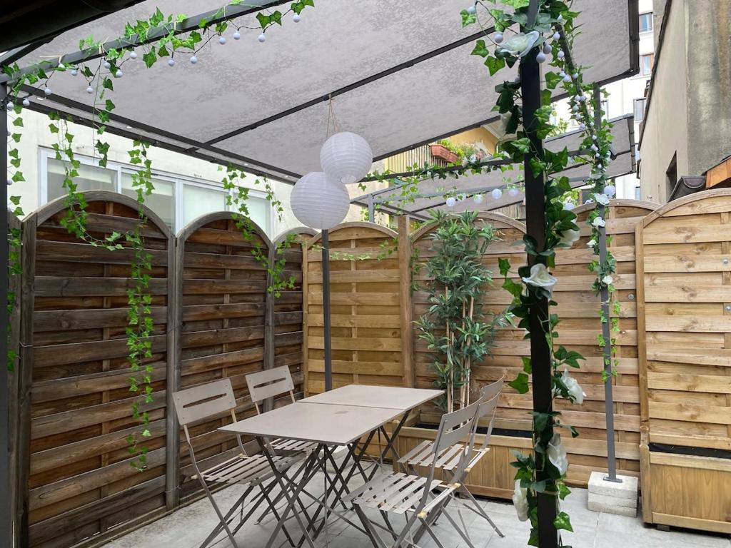 un patio avec une table et des chaises sous une pergola dans l'établissement L'Accalmie, à Annecy