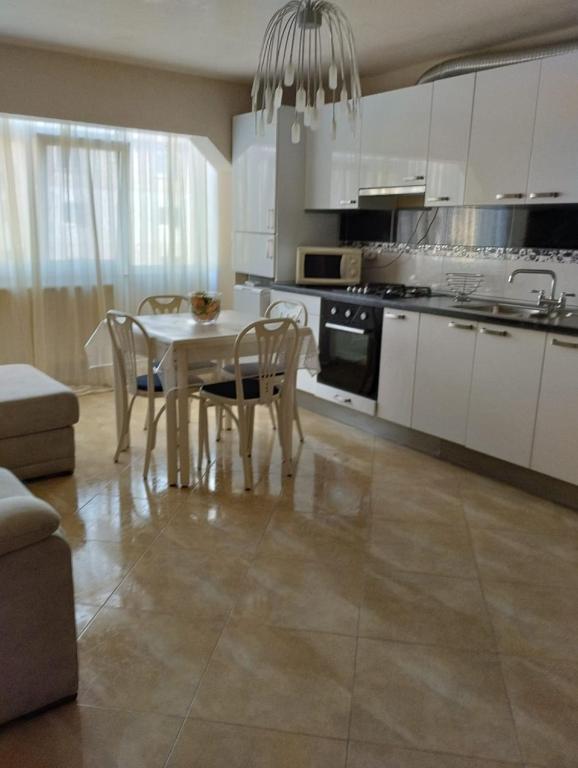 a kitchen with white cabinets and a table and chairs at Apartament zona 1 Decembrie in Tecuci