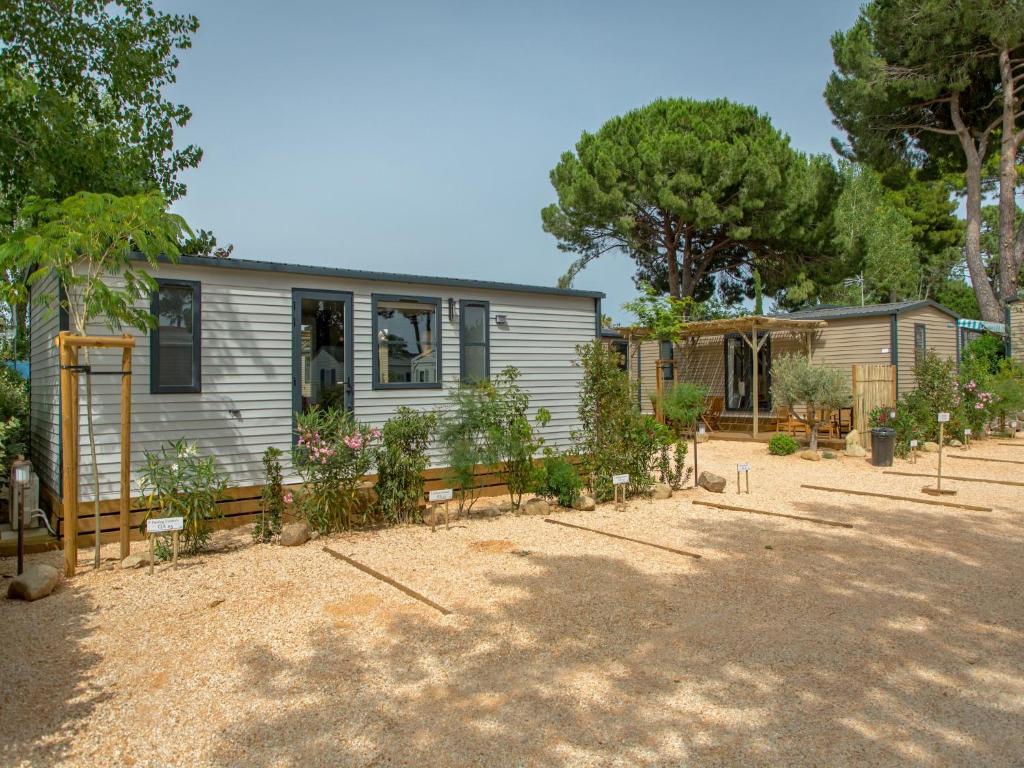une maison avec beaucoup de plantes dans la cour dans l'établissement Mobile Home Near Beach, au Grau-dʼAgde