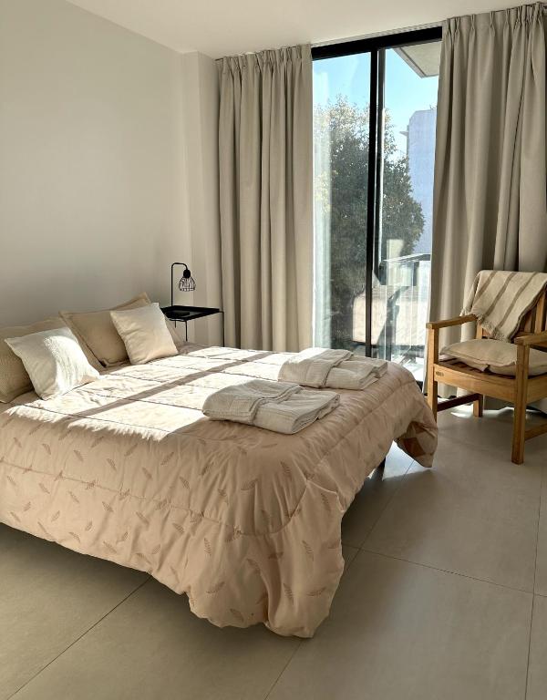 a white bedroom with a large bed and a chair at Zona Güemes 2 ambiente N 503 in Mar del Plata