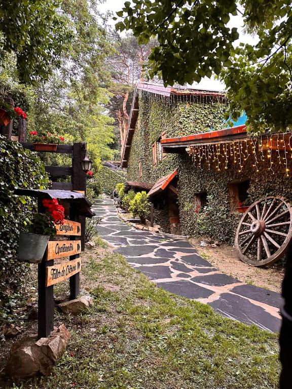 un camino de piedra junto a un edificio con flores en La Posada Cercedilla, en Cercedilla