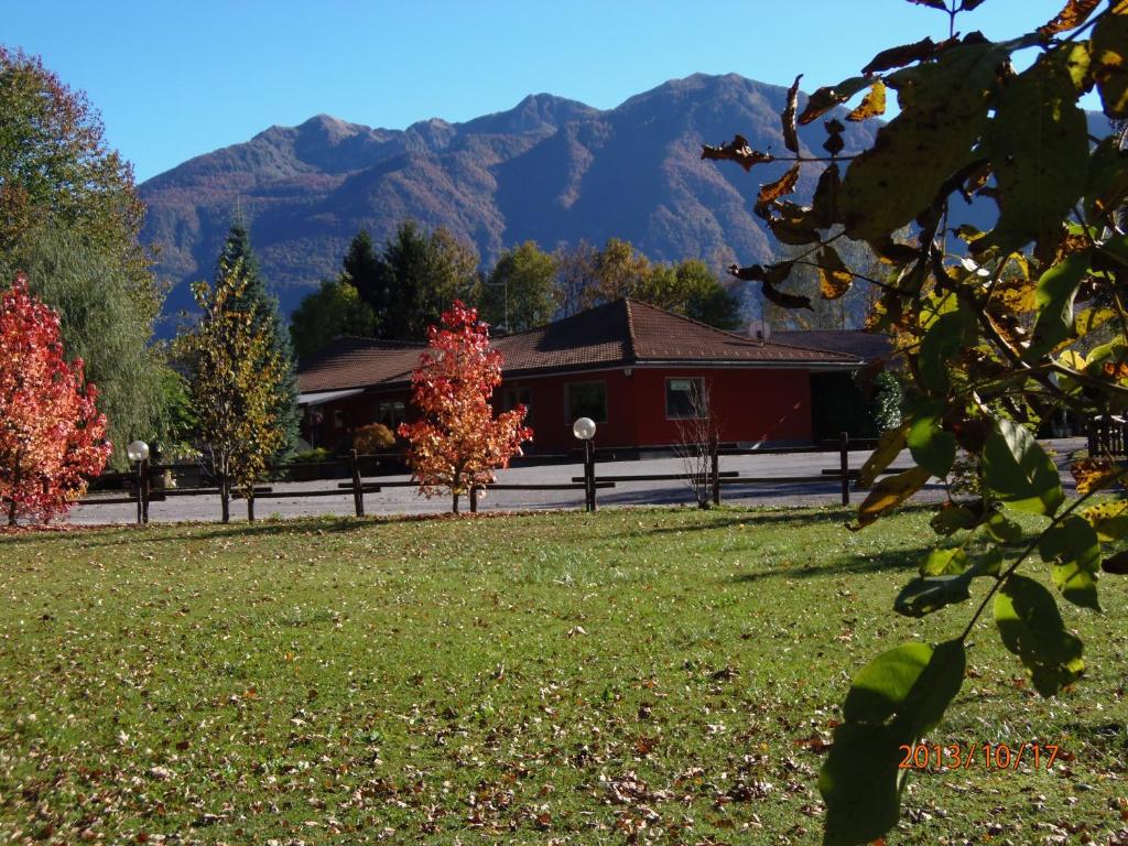 a red building with trees and mountains in the background at Alla Pagoda in Enemonzo