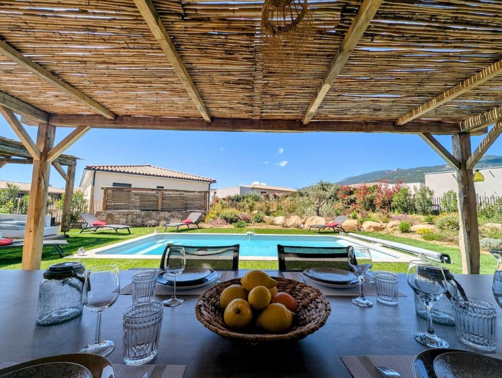 une table avec un bol de fruits sur une table avec une piscine dans l'établissement House with pool, à Lecci