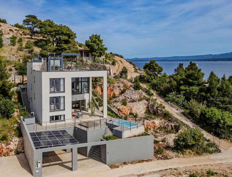 ein Haus mit Sonnenkollektoren an der Seite eines Hügels in der Unterkunft Villa Blue Horizon in Nerežišće