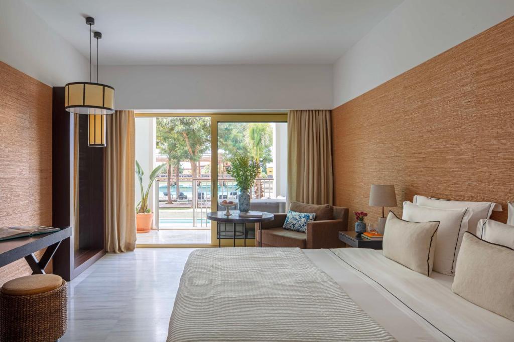a bedroom with a large bed and a living room at Victoria Golf Resort and Spa Managed by Accor in Vilamoura