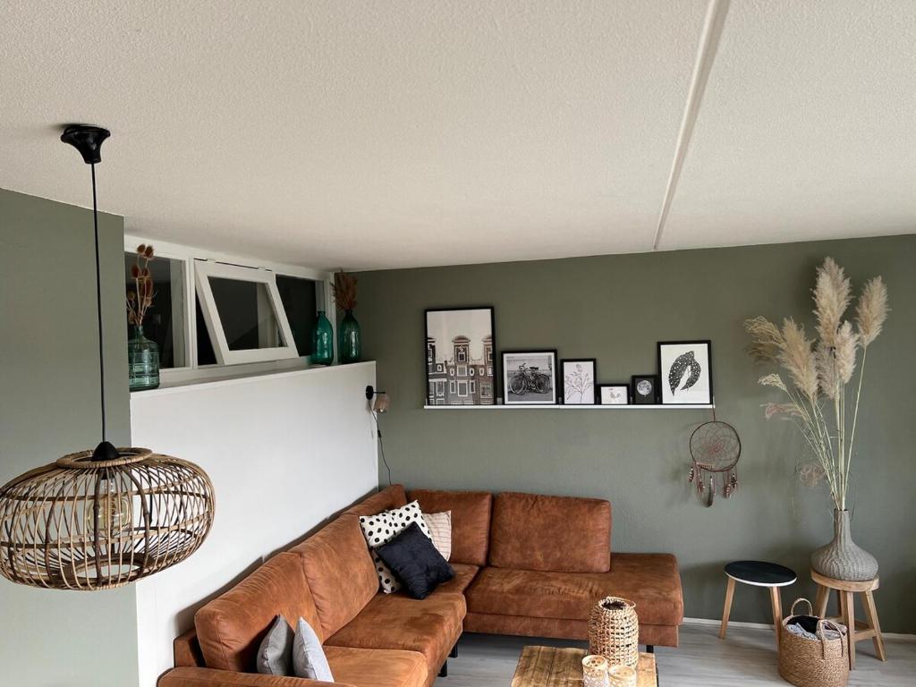 a living room with a brown couch and green walls at Dünenblick am Meer aber 400 meter entfernt, mit renoviertem Badezimmer in Julianadorp