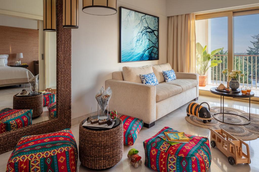 a living room with a couch and some ottoman at Victoria Golf Resort and Spa Managed by Accor in Vilamoura