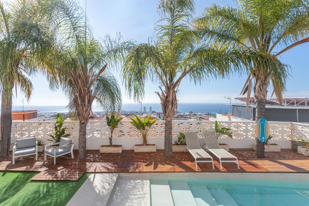 a resort swimming pool with palm trees and the ocean at Casa Valencia in Santa Cruz de Tenerife