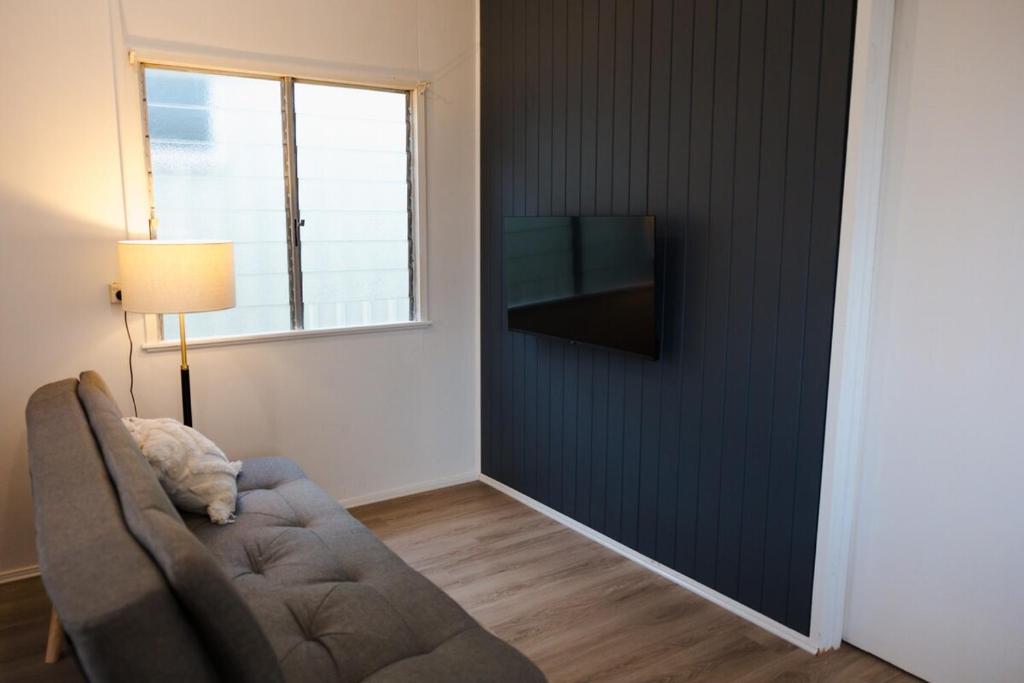 a living room with a couch and a television on a wall at The Little Gem in Clermont