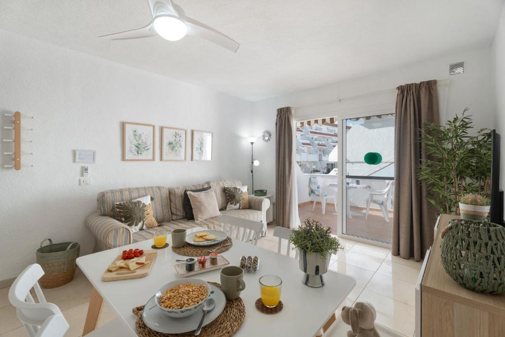 a living room with a couch and a table at Serene Terrace And Pool in Playa de las Americas