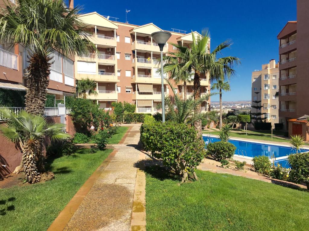 an apartment complex with a swimming pool and palm trees at Apartamentos Arenales Del Sol II in Arenales del Sol