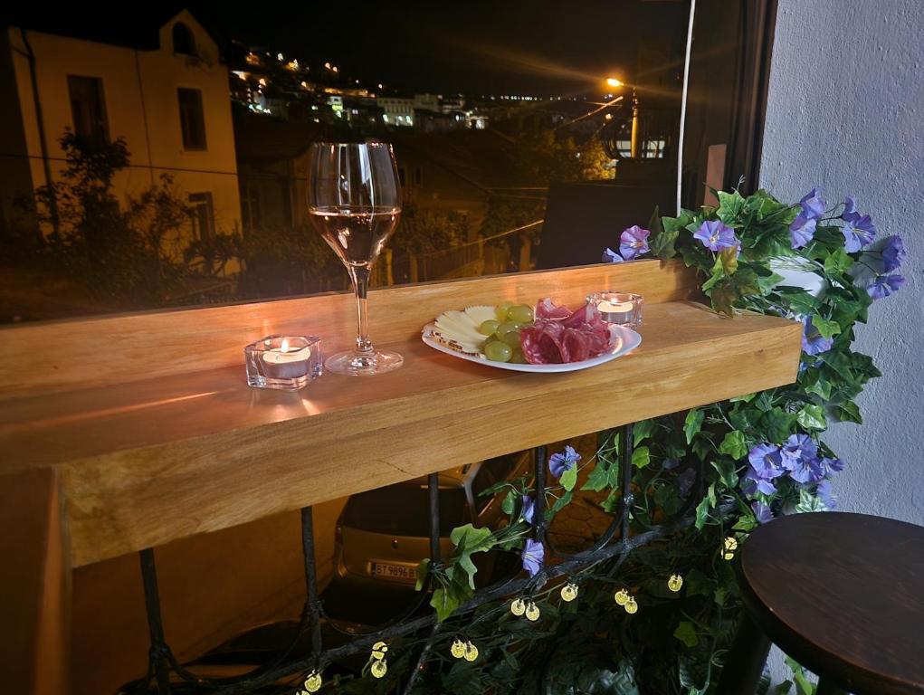 a table with a glass of wine and a plate of food at YaVi's Central Apartment in Veliko Tŭrnovo