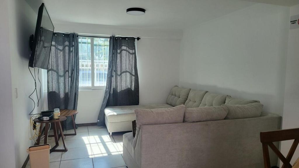 Una sala de estar con un sofá y una ventana. en Casa cerca todo en Zapopan !, en Guadalajara