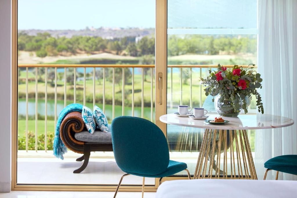 a room with a table and chairs and a balcony at Victoria Golf Resort and Spa Managed by Accor in Vilamoura