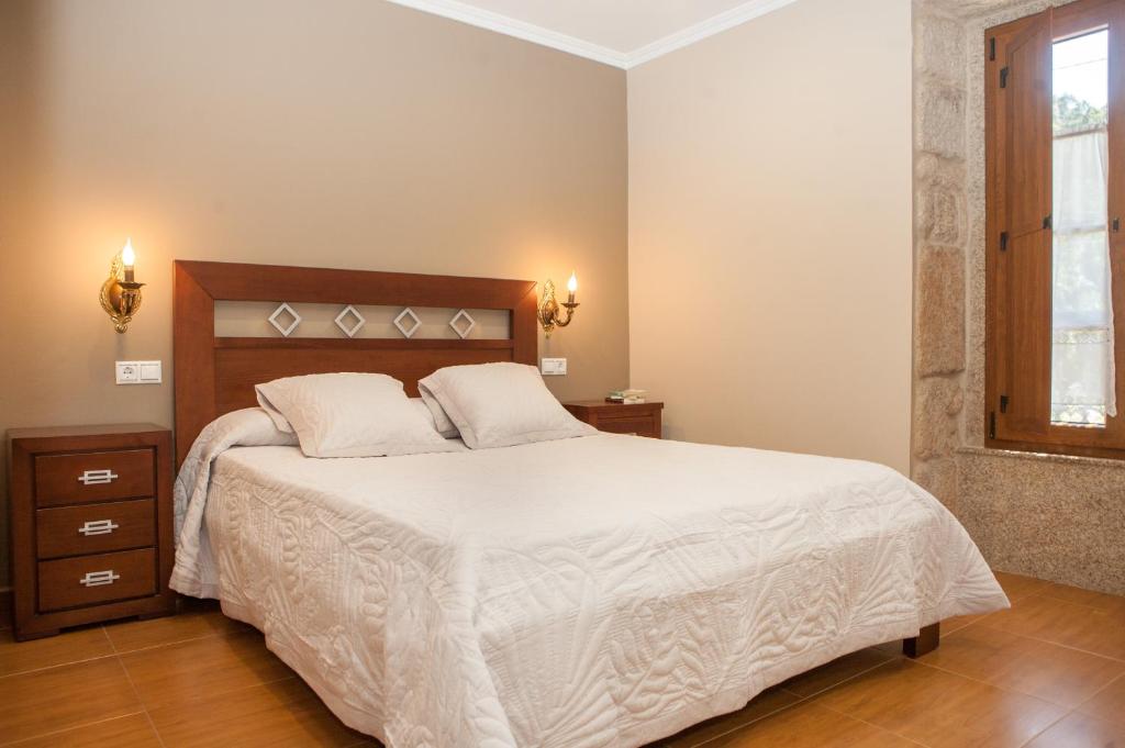 Un dormitorio con una cama grande con sábanas blancas. en Casa De Rama, en San Mamede de Carnota