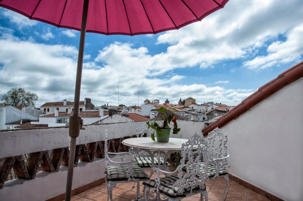 un patio con mesa, sillas y sombrilla en Casa Resende- Free indoor park, en Évora