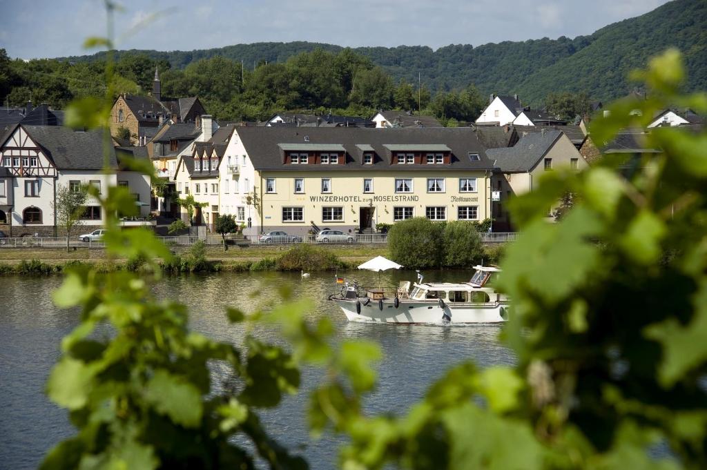 a boat on the water in front of a building at Hotel zum Moselstrand in Briedern