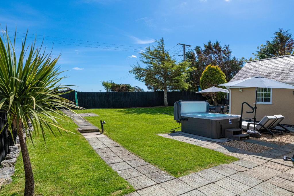 a backyard with a barbecue grill and a house at Felin Traeth Cottage in Rhosneigr