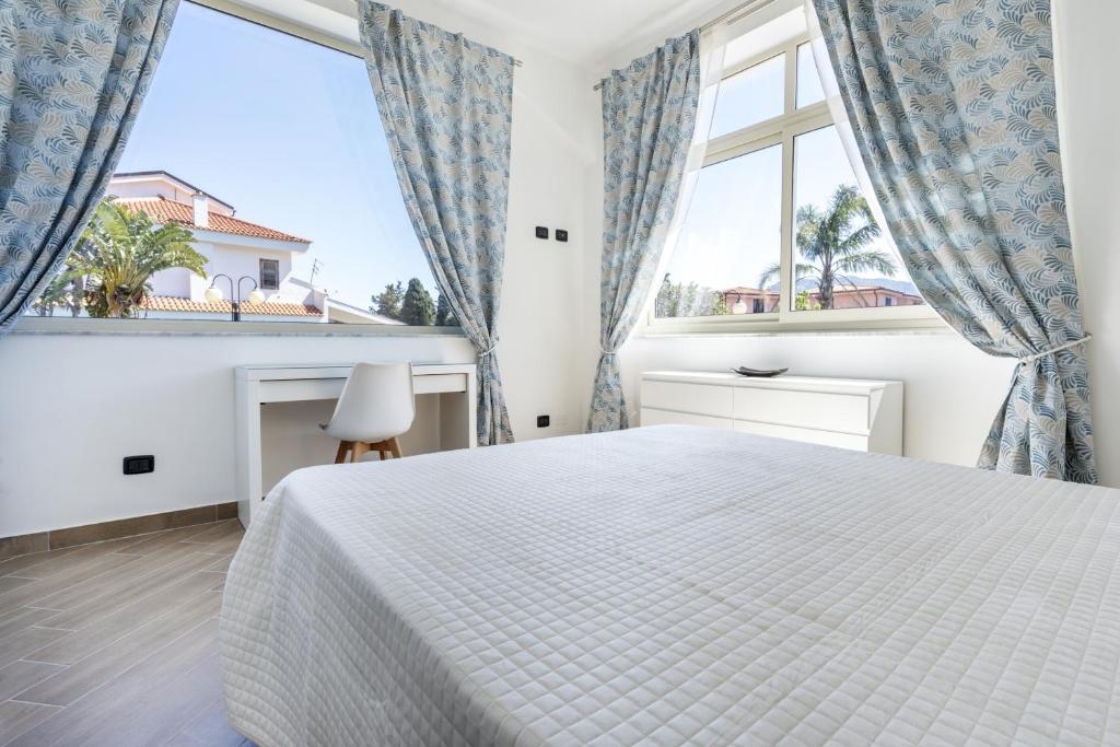 a white bedroom with a bed and two windows at Villa Sandoval in Palermo
