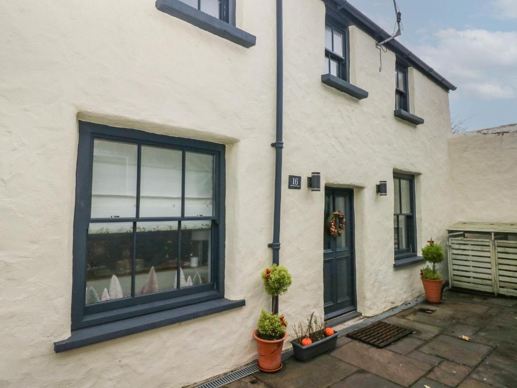 a white house with blue windows and potted plants at Blacksmiths Cottage in Pembroke