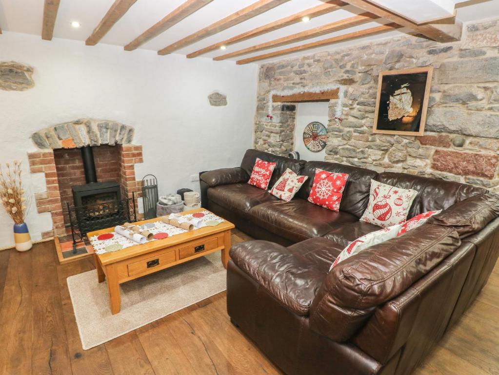a living room with a leather couch and a fireplace at Blacksmiths Cottage in Pembroke